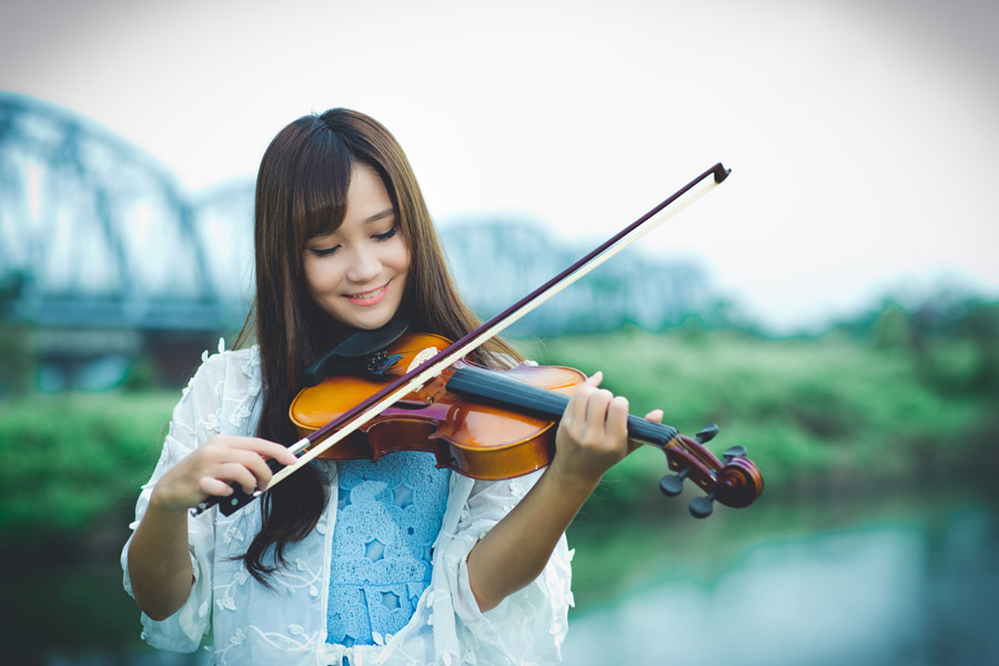 鉄橋のある川辺でバイオリンを弾く台湾人女性