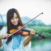 鉄橋のある川辺でバイオリンを弾く台湾人女性
