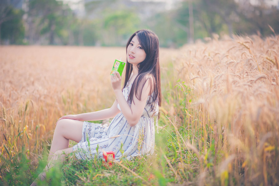 パックの飲み物を持って畦道に座る台湾人女性の写真